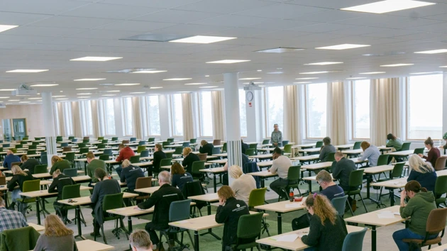 En tentamenssal full med skrivande studenter som koncentrerat fokuserar på sin tenta.