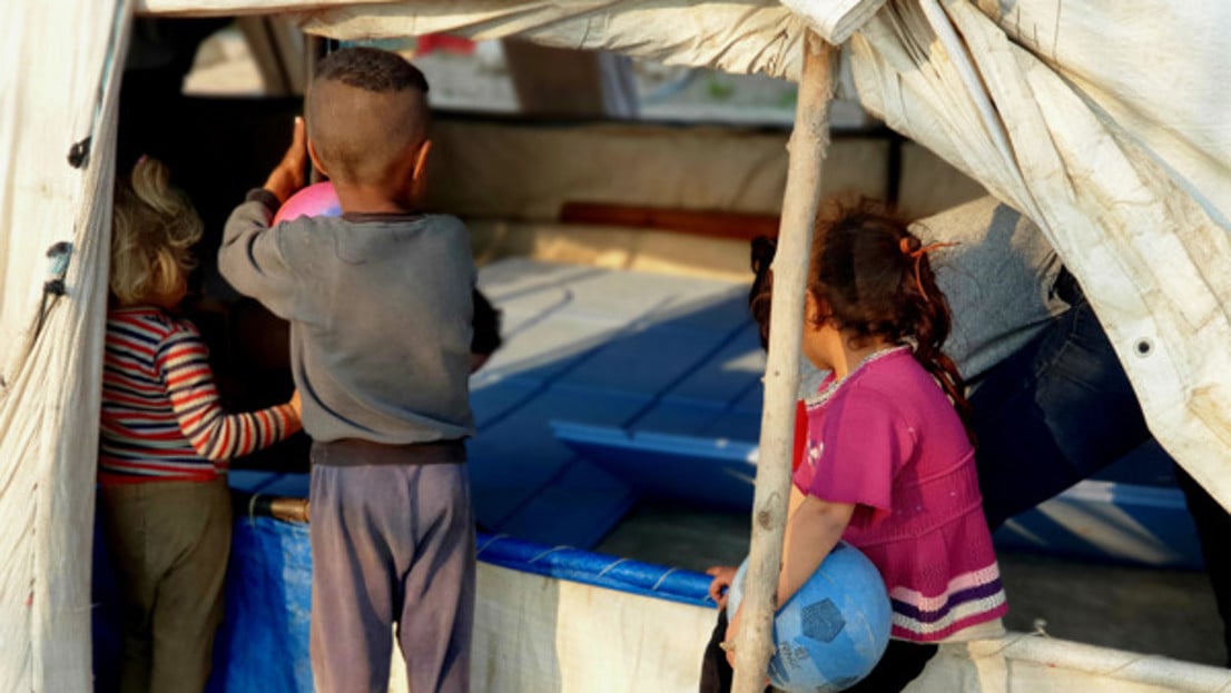 Children in the farm camp watching students installing the prototype in a pilot tent